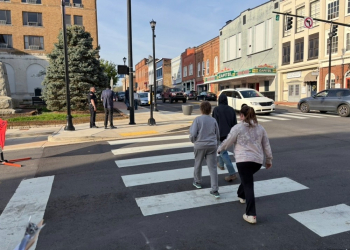 Pedestrians safely cross the street his morning while a Greeneville Police Officer surveys another pedestrian who had just crossed.