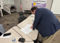 New Greeneville City Director of Schools Dr. Matthew Drinnon signs his contract moments after it was approved.