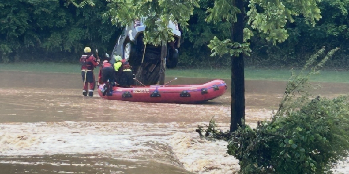 Members of the Caney Branch VFD approach one of dozens of disabled vehicles swept away by the flood waters Thursday.