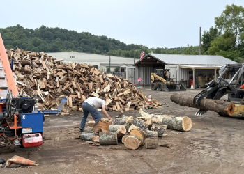 A few volunteers work to split wood at the Greene County Firewood Ministry's new location on West Main Street on Saturday morning. The organization is looking for more volunteers to help process wood for the coming winter.