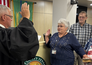 Lori Bryant is sworn in as her sister Linda Ayers holds the Bible.  Behind them is Robert Ayers.