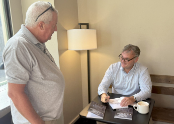 Former Greeneville City Manager Todd Smith, right, signs a copy of his new book for a friend at Catalyst Coffee Company on Tuesday.