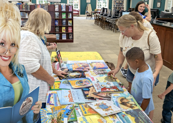 Parents and their children look through a table of free books during a celebration of Dolly Parton and the Greene County Imagination Library on Tuesday at the Greeneville/Greene County Library.