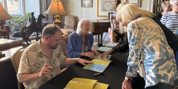 Marilyn duBrisk, seated center, and Parker Bunch, seated at left, sign copies of a new children's book the pair recently produced on Thursday afternoon.